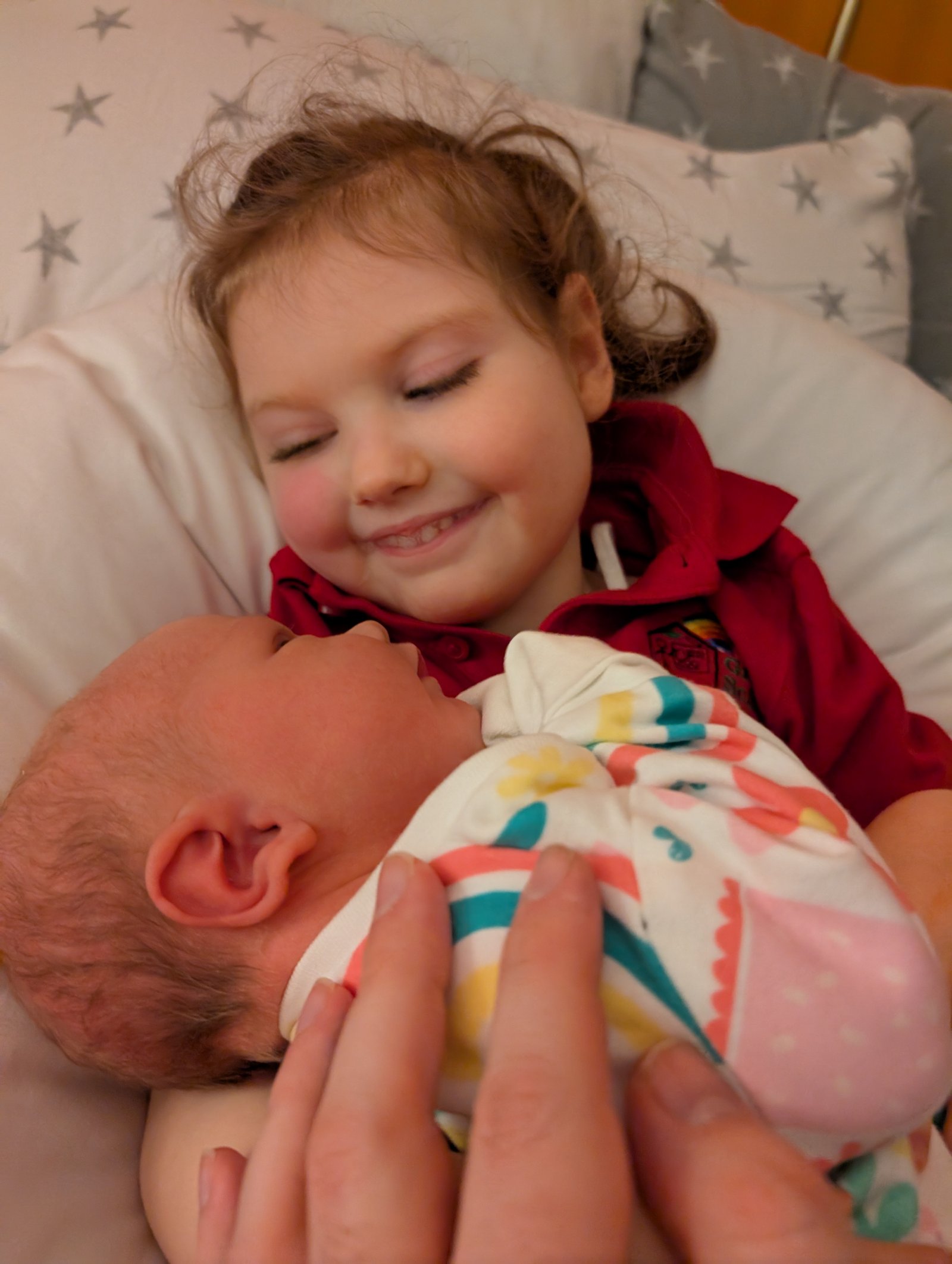 Grace smiling with her new baby sibling